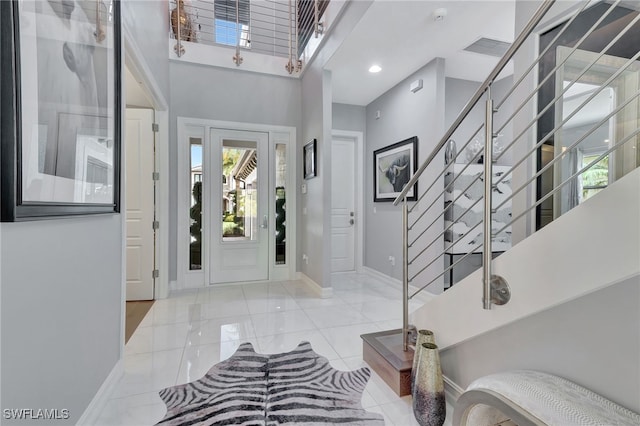 tiled entrance foyer featuring a healthy amount of sunlight and a high ceiling