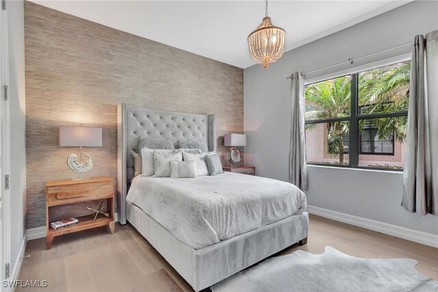 14690 Reserve Pl, Naples, FL 34109 - bedroom with an accent wall, baseboards, a chandelier, and light wood finished floors