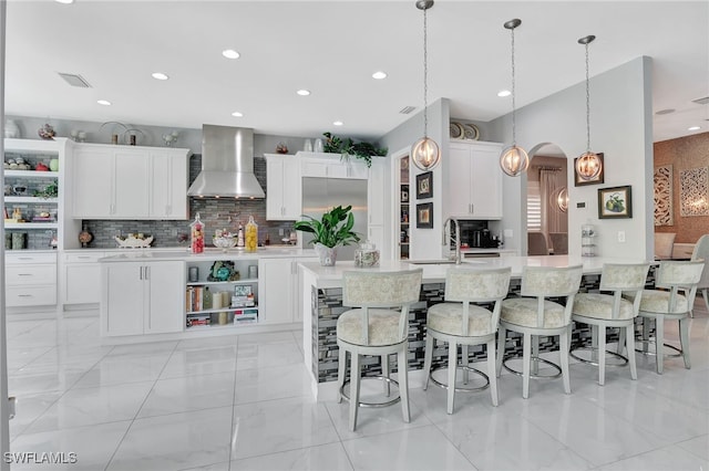 14690 Reserve Pl, Naples, FL 34109 - kitchen featuring wall chimney range hood, open shelves, backsplash, recessed lighting, and a kitchen island with sink