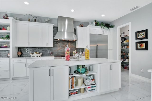 14690 Reserve Pl, Naples, FL 34109 - kitchen featuring wall chimney range hood, built in fridge, light marble finish flooring, light countertops, and white cabinets