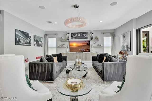 living room featuring a fireplace, plenty of natural light, and a notable chandelier