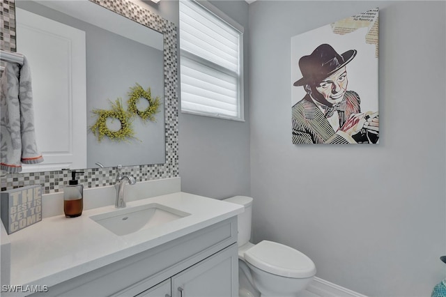 bathroom featuring vanity, toilet, and tasteful backsplash