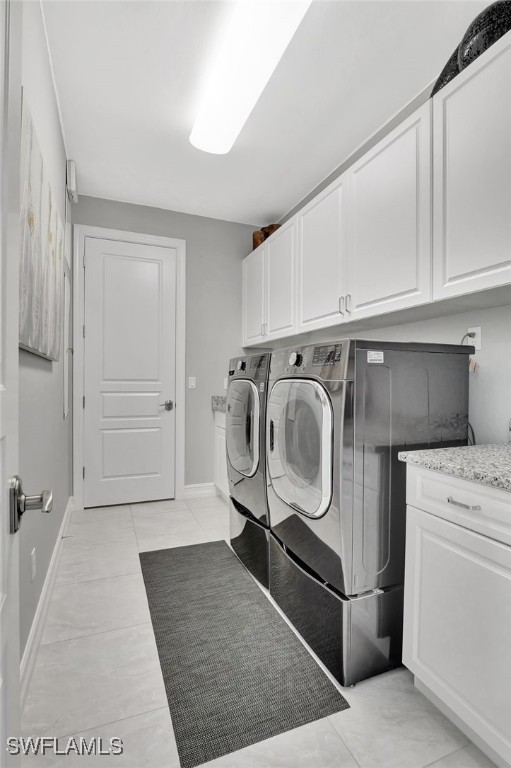 14690 Reserve Pl, Naples, FL 34109 - clothes washing area featuring cabinet space, washer and dryer, and baseboards