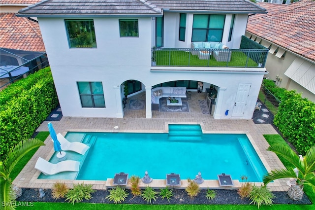 rear view of house with an outdoor living space, a fenced in pool, and a patio area