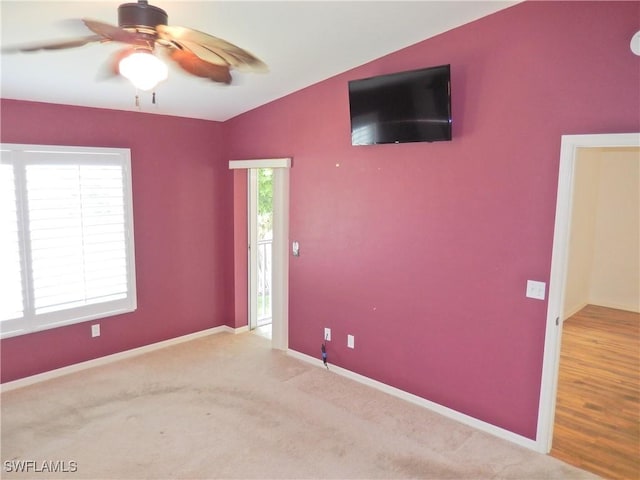 spare room featuring lofted ceiling, light colored carpet, and ceiling fan