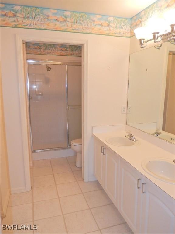 bathroom featuring vanity, toilet, a shower with door, tile patterned floors, and an inviting chandelier