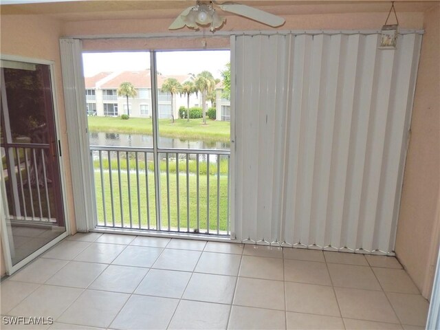 interior space with ceiling fan, a water view, and light tile patterned floors