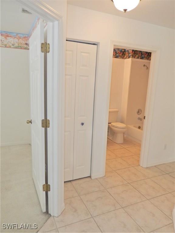 interior space with toilet, tile patterned floors, and bathing tub / shower combination