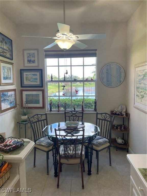 dining area featuring a water view, light tile patterned floors, and ceiling fan