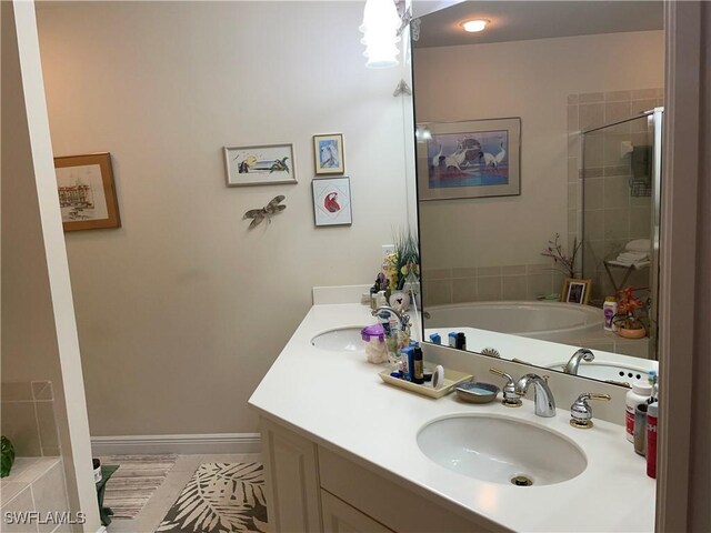 full bath featuring double vanity, a garden tub, a sink, and tiled shower