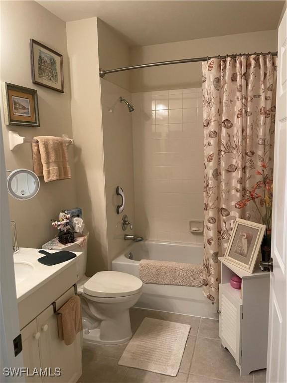 bathroom with shower / bath combination with curtain, tile patterned flooring, vanity, and toilet