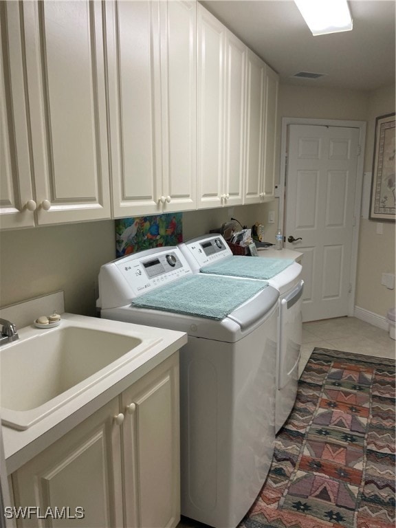 washroom featuring washing machine and clothes dryer, cabinets, sink, and light tile patterned floors