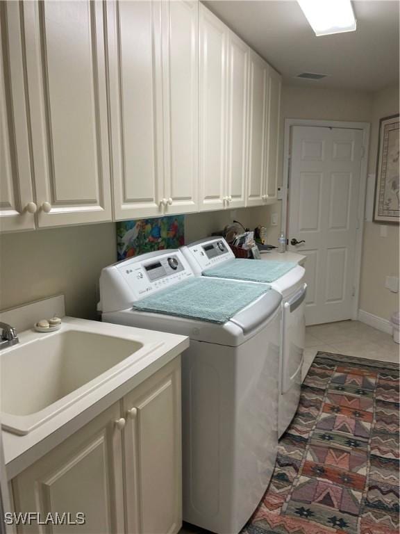 laundry room with a sink, visible vents, baseboards, cabinet space, and washer and clothes dryer