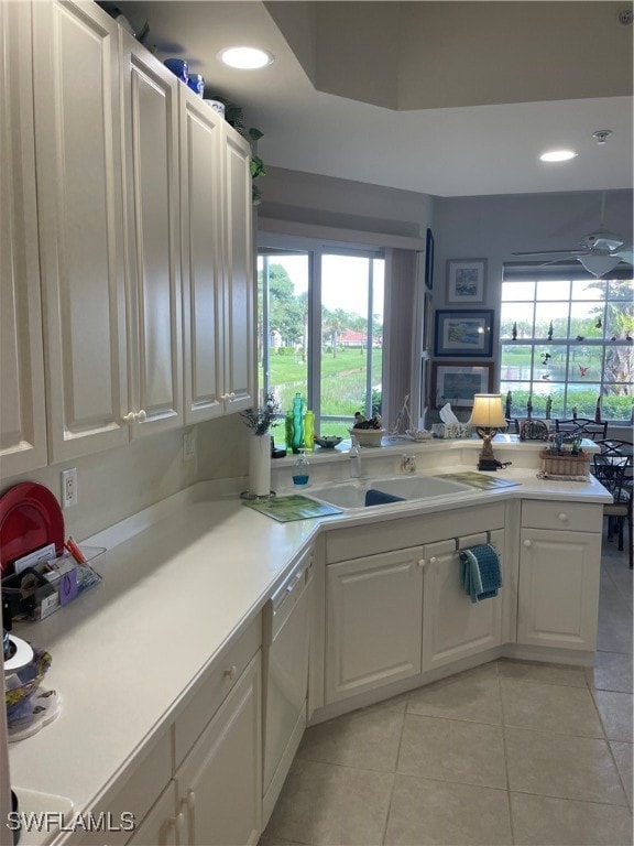 kitchen featuring white dishwasher, plenty of natural light, and white cabinets