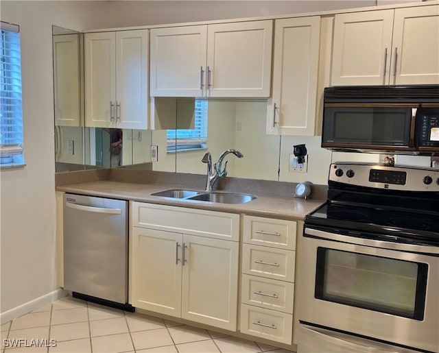 kitchen with white cabinetry, light tile patterned floors, stainless steel appliances, a healthy amount of sunlight, and sink