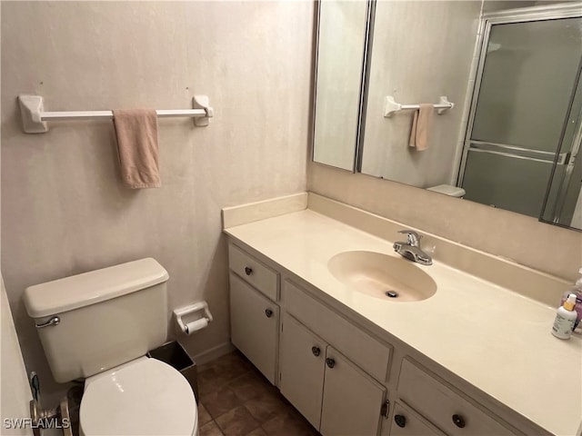 bathroom with tile patterned floors, a shower with door, vanity, and toilet