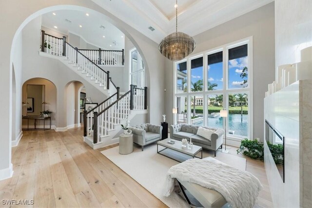 interior space featuring crown molding, a high ceiling, light wood-type flooring, and a chandelier