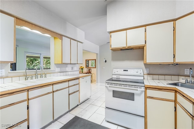 kitchen featuring white appliances, tile counters, light tile patterned flooring, and sink