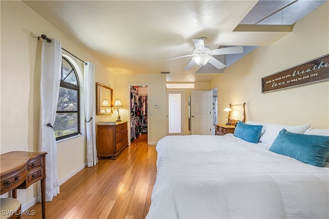 bedroom with light wood-type flooring, a spacious closet, ceiling fan, and a closet