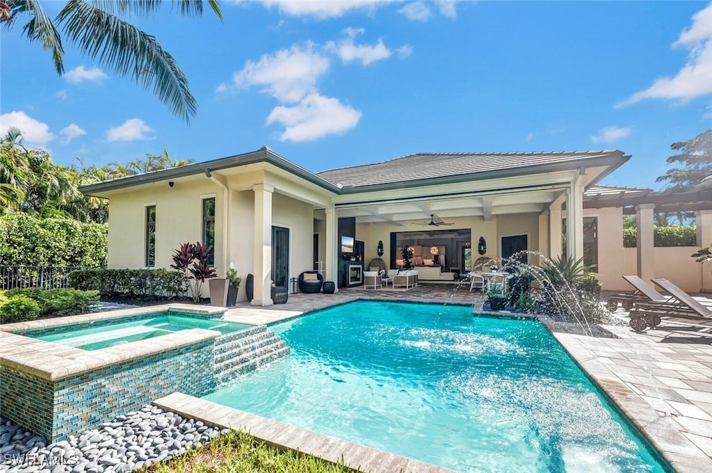 view of swimming pool featuring pool water feature, ceiling fan, an in ground hot tub, and a patio