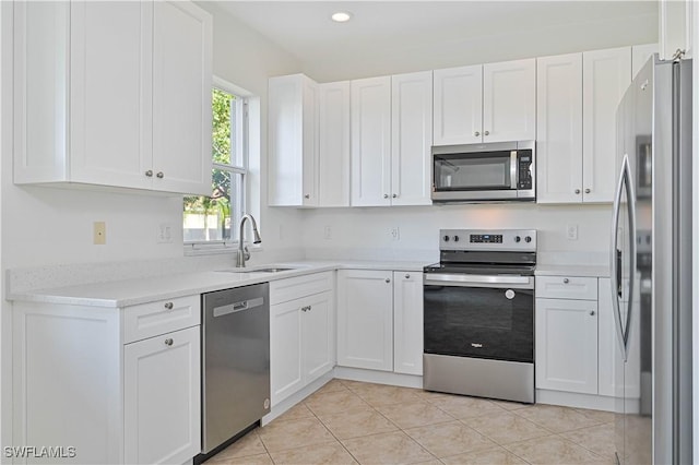 kitchen featuring appliances with stainless steel finishes, sink, white cabinetry, and light tile patterned flooring