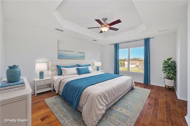 bedroom featuring a raised ceiling, ceiling fan, and dark hardwood / wood-style flooring