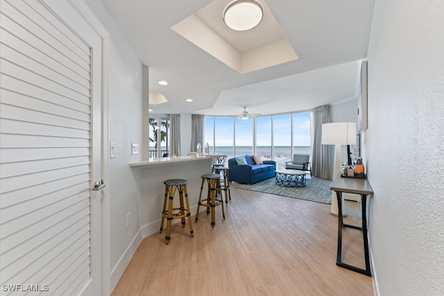 kitchen featuring light wood-type flooring, a water view, a kitchen breakfast bar, kitchen peninsula, and ceiling fan