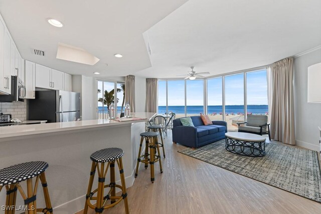 kitchen with a water view, stainless steel appliances, white cabinetry, and a breakfast bar