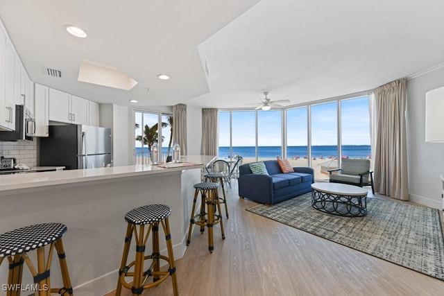200 Estero Blvd Unit 101, Fort Myers Beach, FL 33931 - kitchen with visible vents, stainless steel appliances, light wood finished floors, a wall of windows, and decorative backsplash