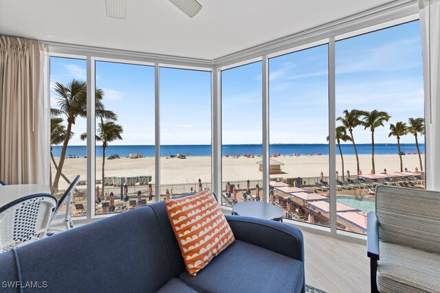 sunroom featuring a water view and a beach view