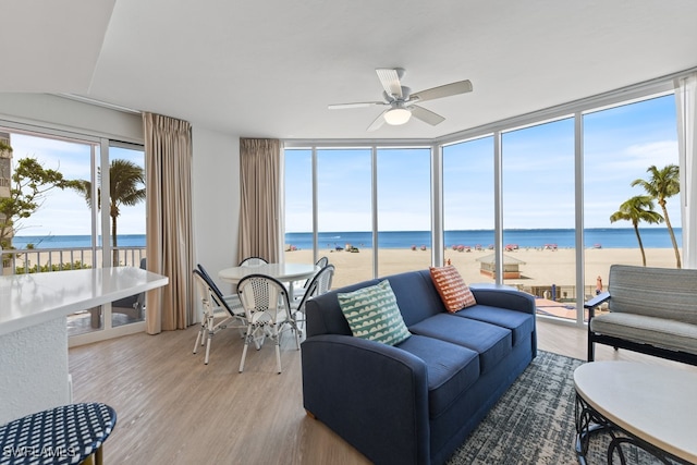 sunroom / solarium featuring a water view, ceiling fan, and a view of the beach