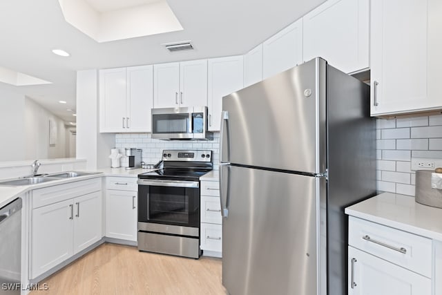 kitchen with stainless steel appliances, sink, light wood-type flooring, and white cabinetry