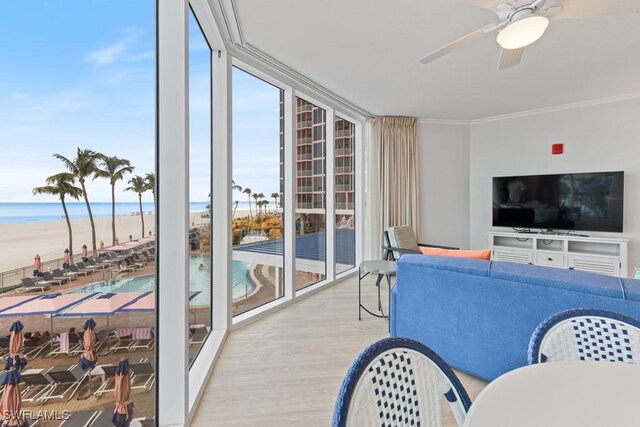 living room with a beach view, a wall of windows, a water view, wood-type flooring, and ceiling fan