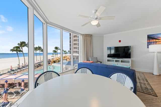 interior space featuring a water view, ornamental molding, a beach view, ceiling fan, and hardwood / wood-style flooring