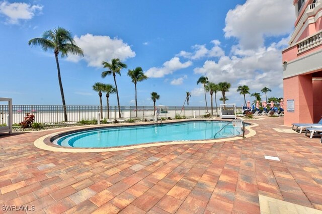 view of pool featuring a water view and a patio