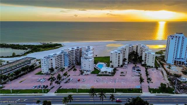 aerial view at dusk featuring a beach view and a water view