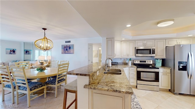 kitchen with appliances with stainless steel finishes, hanging light fixtures, an inviting chandelier, sink, and kitchen peninsula