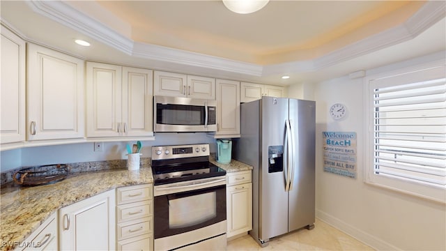 kitchen with a tray ceiling, ornamental molding, and stainless steel appliances