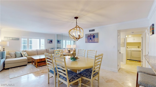 dining area featuring a chandelier, washer and dryer, and ornamental molding