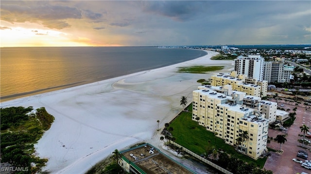 aerial view at dusk with a beach view and a water view