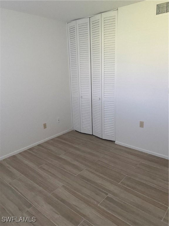 unfurnished bedroom with baseboards, a closet, visible vents, and wood tiled floor