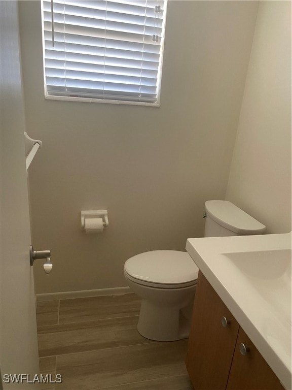 bathroom with vanity, wood finished floors, toilet, and baseboards