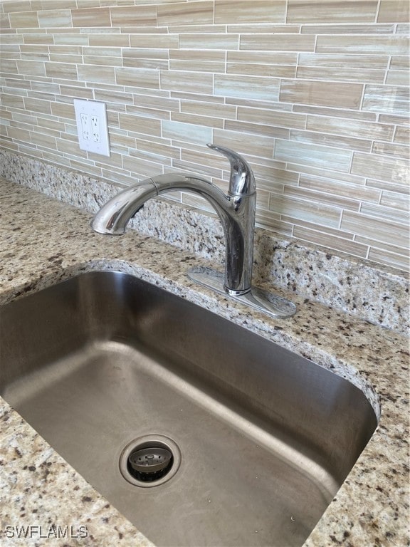 interior details featuring light stone counters and a sink