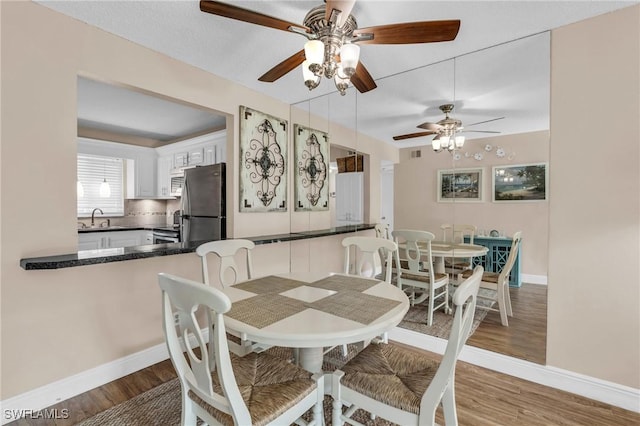 dining room with hardwood / wood-style flooring, ceiling fan, and sink