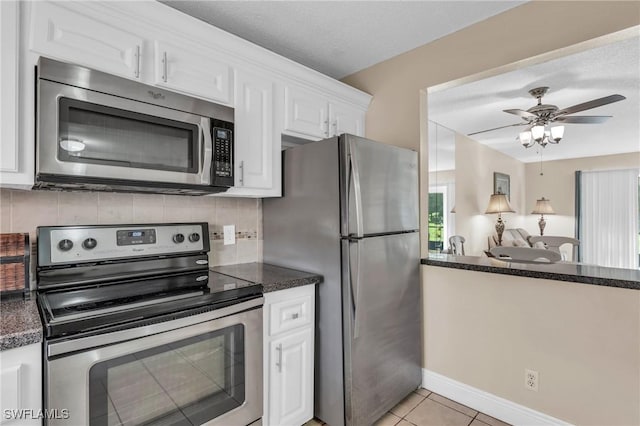 kitchen with ceiling fan, light tile patterned floors, appliances with stainless steel finishes, tasteful backsplash, and white cabinetry