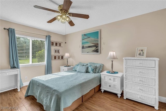 bedroom with hardwood / wood-style flooring, ceiling fan, and a textured ceiling