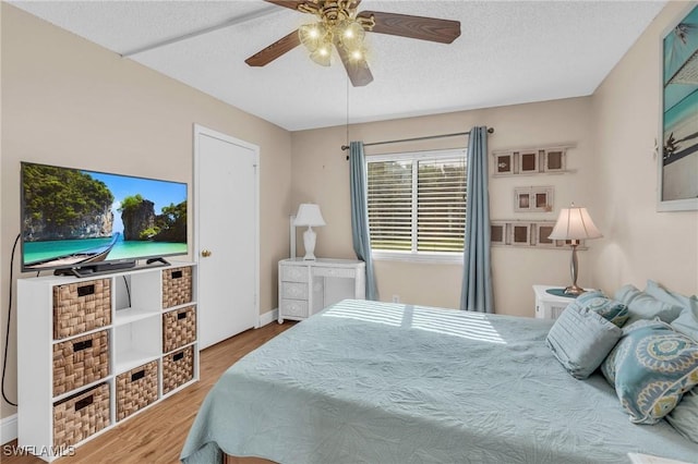 bedroom featuring ceiling fan, hardwood / wood-style floors, and a textured ceiling