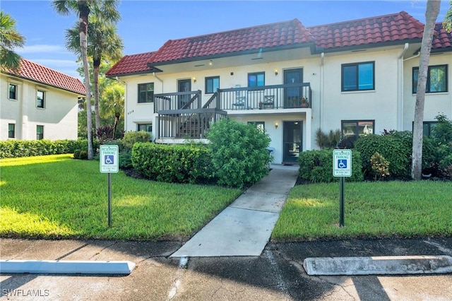 4318 27th Ct SW Unit 102, Naples, FL 34116 - view of property featuring a tiled roof, a front lawn, a balcony, and stucco siding