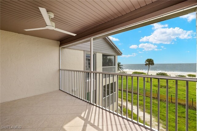 balcony featuring a water view, a beach view, and ceiling fan