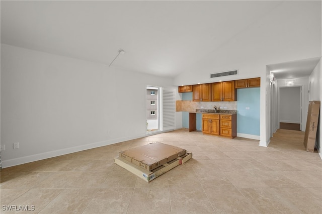 unfurnished living room featuring sink, light tile patterned floors, and high vaulted ceiling